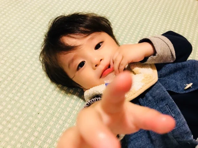 仰向けで指をカメラに向ける男幼児