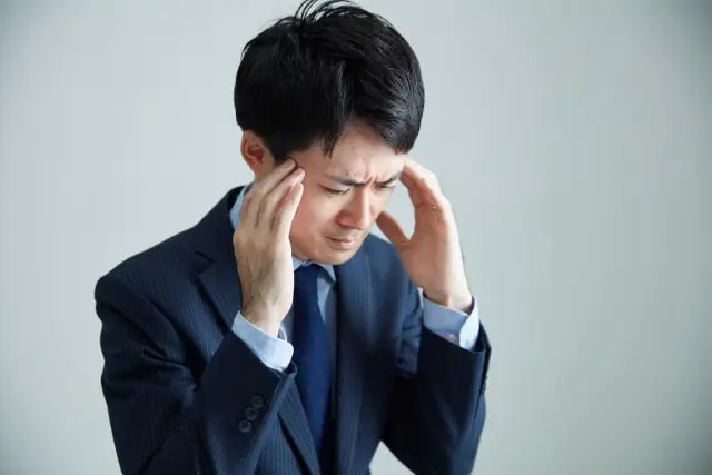 指差呼称が恥ずかしくて頭を抱えるビジネスマン